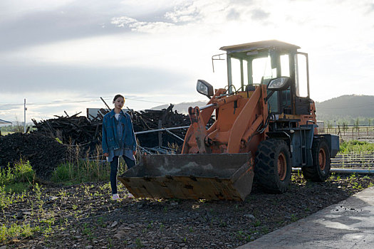 草原傍晚一台废弃的挖掘机和一位身穿牛仔的女孩的合影