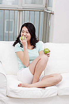 年轻女士坐在沙发上拿着苹果
