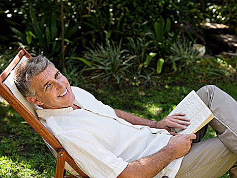 男人,坐,折叠躺椅,花园,书本