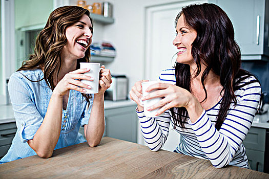 高兴,女性朋友,拿着,咖啡杯,讨论,桌子,厨房