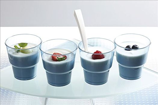 四个,蓝色,酸奶,杯子,水果,树莓,草莓,蓝莓,小,薄荷叶,勺子,玻璃,台案