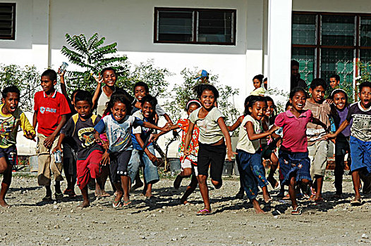 three,3,timorese,girl,in,a,refugee,camp,pointing,to,the,air