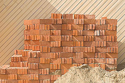 木板墙前的一个砖垛和一堆沙子apileofbricksandsandbeforeawoodenwallbackground
