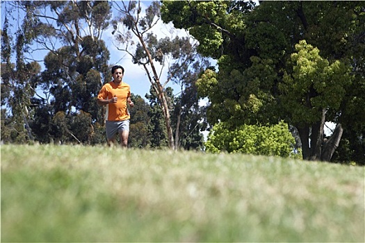 男人,穿,橙色,t恤,短裤,慢跑,草地,公园,贴地拍摄,背景聚焦