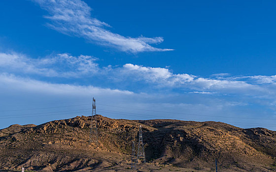 新疆蓝天白云下戈壁山丘电塔