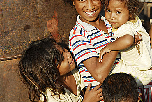 group,of,timorese,children,in,front,iron,tile,wall,with,rust
