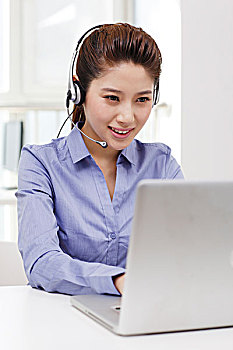 商务女士头戴耳机使用笔记本电脑