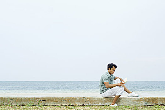 男人,坐,海滩,读,书本,侧面视角