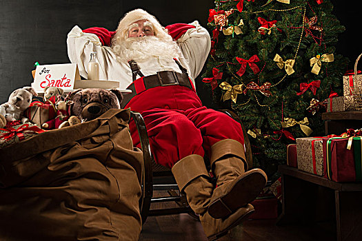 圣诞老人,手放头后,放松,在家,坐,舒适,扶手椅,靠近,圣诞树,喝,牛奶,吃,清新,饼干,罪孽,桌上