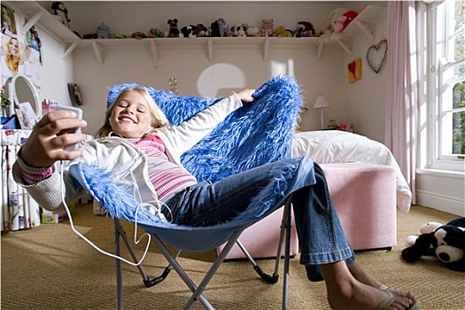 女孩,8-10岁,卧室,蓝色背景,粗毛,堆,椅子,听,mp3播放器,微笑