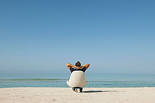 男人,坐,扶手椅,海滩,看,海洋,后视图