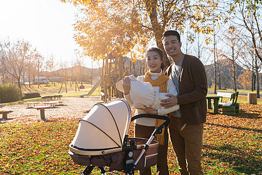 年轻夫妻推着婴儿车散步