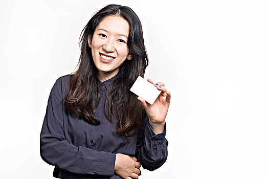 在白色背景前手持卡片微笑的亚洲女性