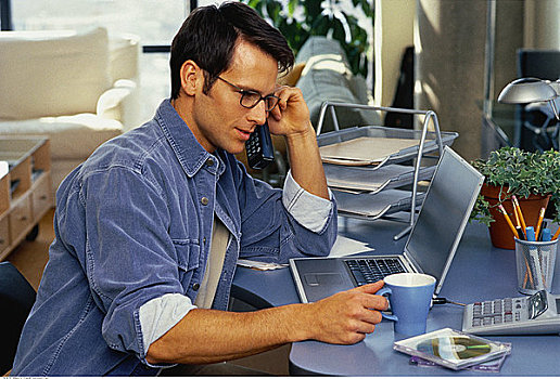 男人,坐,书桌,笔记本电脑,无绳电话