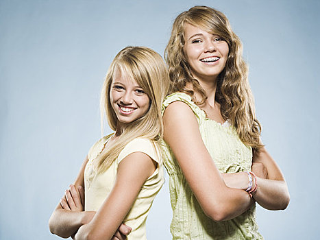 两个女孩,微笑,双臂交叉,背对背