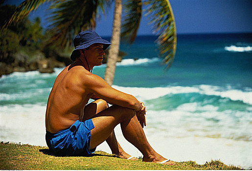 男人,坐,草地,靠近,海滩,多米尼加共和国,加勒比海