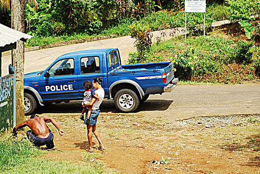 dominica,carib,territory,woman,with,baby,walking,in,front,of,police,car