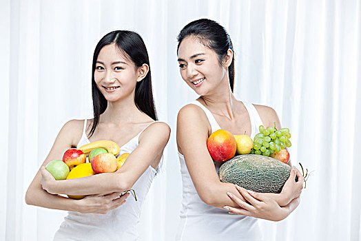 两个抱着水果的亚洲青年女性