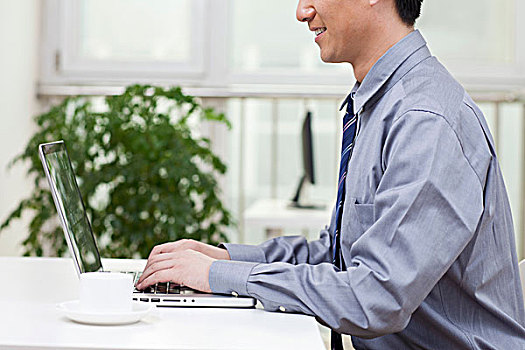 一个在办公室用电脑的青年商务男士