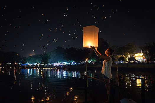 泰国清迈水灯节期间,一名西方女性在清迈湄平河边手持孔明灯正准备放飞