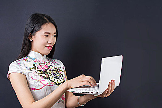 穿旗袍的女孩拿着白色电脑