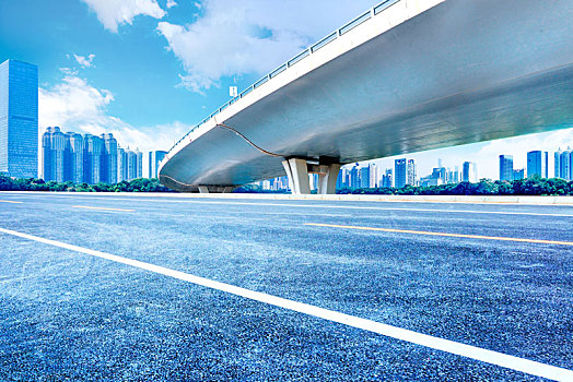 立交桥下,无车的沥青道路,现代城市建筑天际线为背景