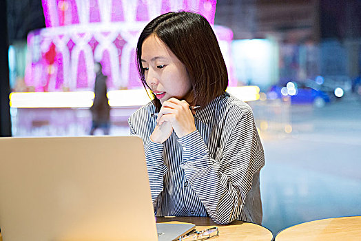 年轻的女性在咖啡馆中工作,坐在笔记本电脑前