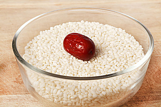 透明玻璃碗盛着白色的糯米并点缀着红枣