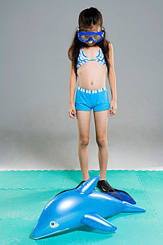 穿着泳衣戴着潜水镜的小女孩对着镜头微笑