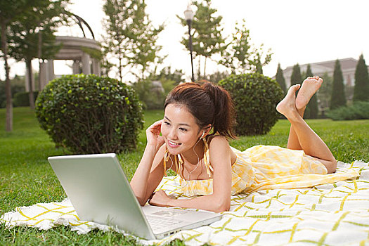 年輕女孩趴在草地上聽音樂
