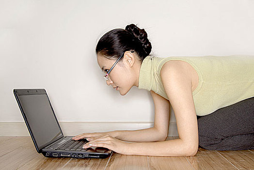 趴在地板上使用电脑的年轻女人