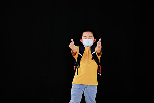 一个戴口罩的小男孩伸出大拇指