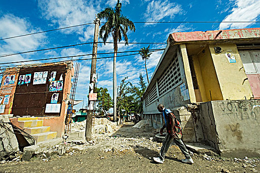 haiti,port,au,prince,man,walking,in,front,of,destroyed,house