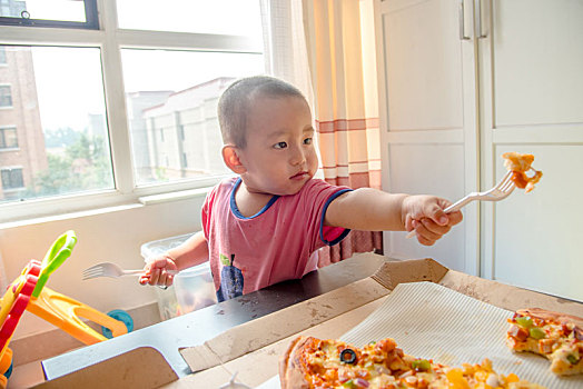 儿童用叉子叉着披萨