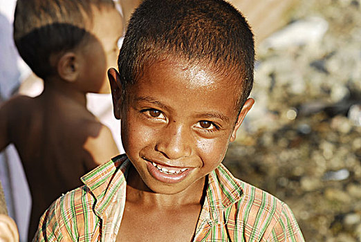 portrait,of,boy,with,white,teeth,and,dark,skin,an,open,shirt,other,in,blurred,background