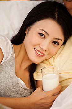 年轻人女躺在床上喝牛奶