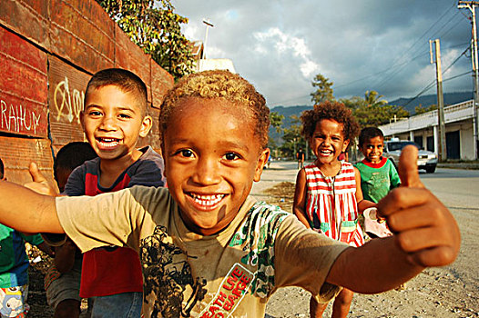 group,of,timorese,children,running,in,the,street,under,dark,clouds,with,a,blond,boy,middle