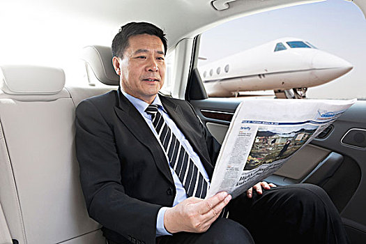 商务男士坐在轿车里看报纸
