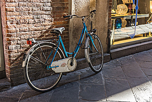 意大利小镇卢卡街道砖墙停靠的古老自行车