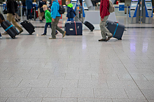 国外渡假旅行,机场大厅人来人往,拖着行李的一家人
