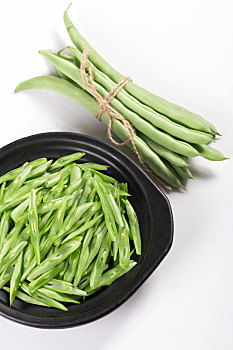 保健蔬菜一盘四季豆丝和一捆四季豆摆放在桌面上