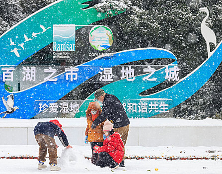 冬天大雪中公园里正在堆雪人的小朋友们