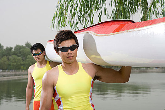 皮划艇运动员扛着皮划艇在岸上走