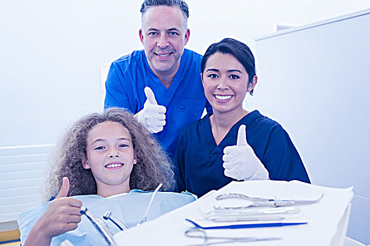 儿科,牙医,协助,小女孩,看镜头,微笑,竖大拇指,牙科诊所