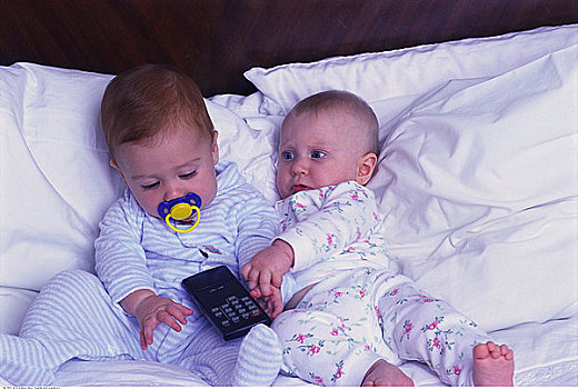 两个,婴儿,躺着,床,拿着,电视遥控器,控制