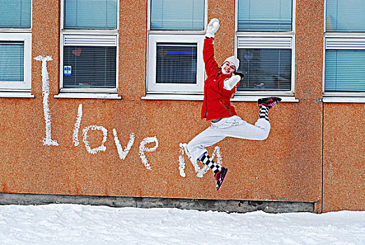 iceland,reykjavik,girls,jumping,in,the,snow,with,school,building,on,background