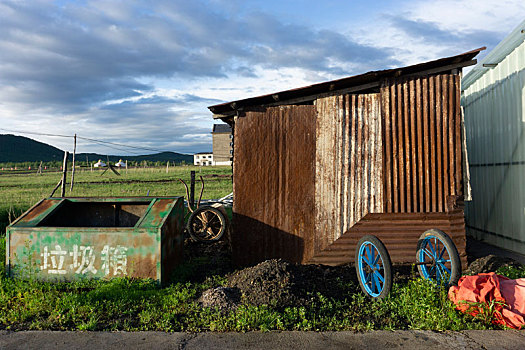草原上的生锈垃圾桶和铁皮屋