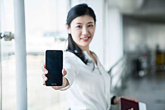 年轻商务女士在机场展示手机