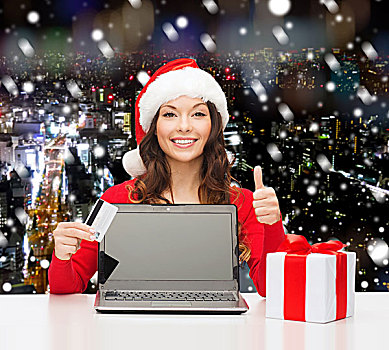 圣诞节,休假,科技,购物,概念,微笑,女人,圣诞老人,帽子,信用卡,礼盒,笔记本电脑,展示,竖大拇指,手势,上方,雪,夜晚,城市,背景