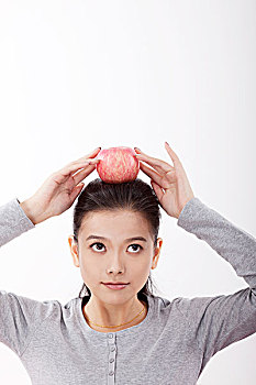东方时尚女性拿着红苹果放在头顶